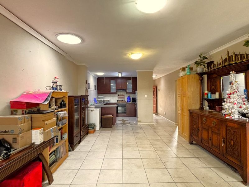 Open plan living and kitchen area featuring tiled flooring, built-in cabinetry, and integrated cooking appliances, offering a functional layout with potential for modernization.