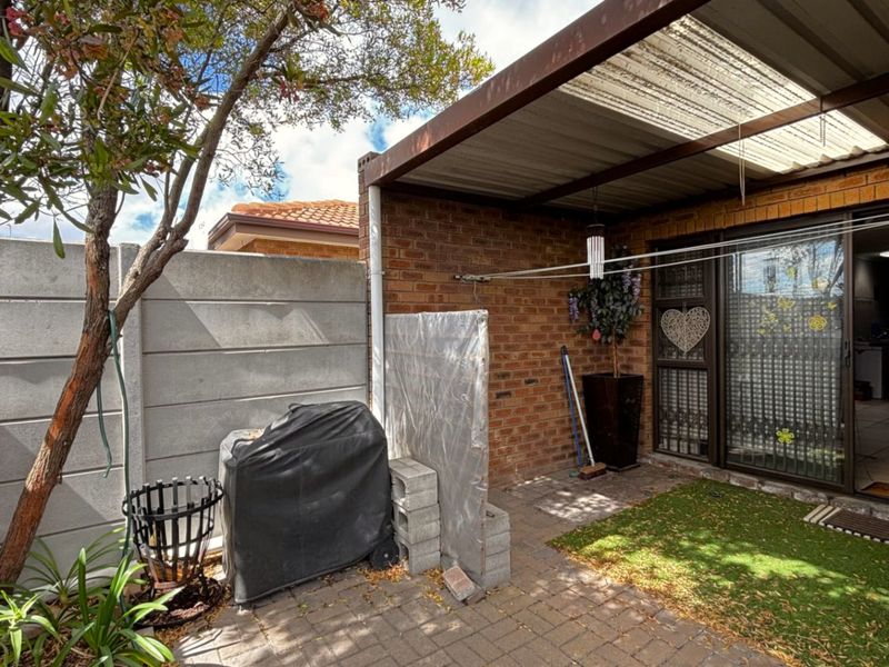 A covered outdoor patio area featuring brick walls, paved flooring, and a sliding glass door providing access to the interior living space.