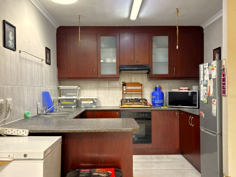 A functional kitchen featuring dark wood cabinetry, laminate countertops, a built-in oven, and a tiled backsplash, offering a practical layout for daily meal preparation.