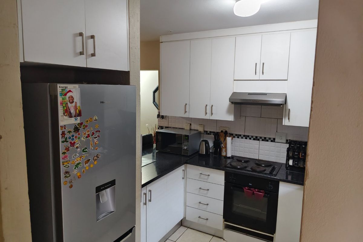 A functional kitchen featuring white cabinetry, black granite countertops, a built-in oven, electric hob, and tiled backsplash.