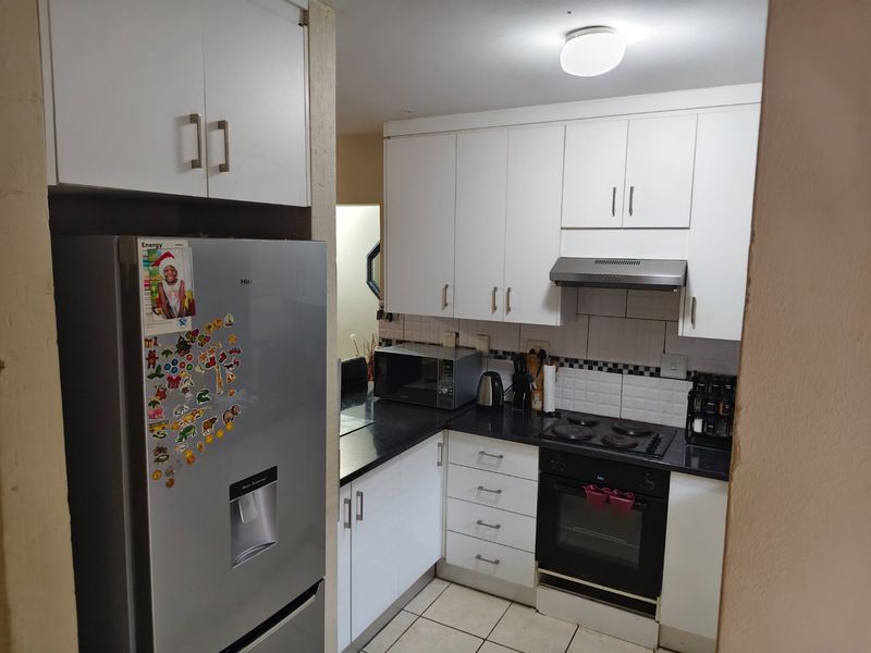 A functional kitchen featuring white cabinetry, black granite countertops, a built-in oven, electric hob, and tiled backsplash.