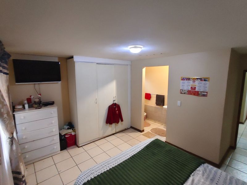 A bedroom featuring tiled flooring, a built-in wardrobe, and an adjoining en-suite bathroom area.