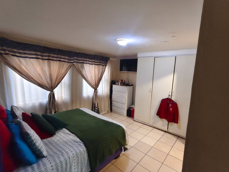 A bedroom featuring tiled flooring and built-in cupboards, with visible ceiling water staining requiring attention.