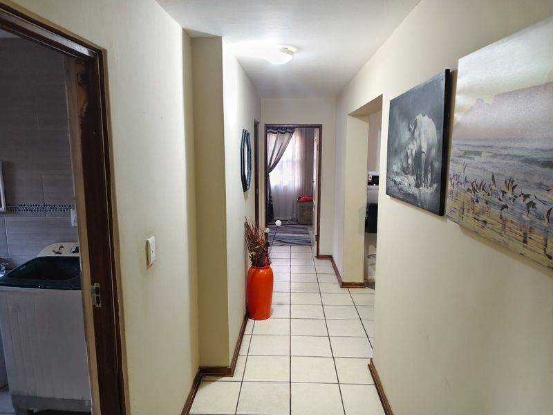 A functional hallway featuring tiled flooring and access to adjacent rooms, including a laundry area.