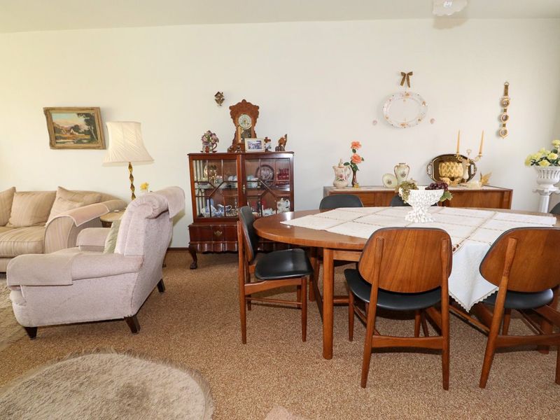 Open plan living and dining area featuring neutral wall finishes and carpeted flooring throughout.