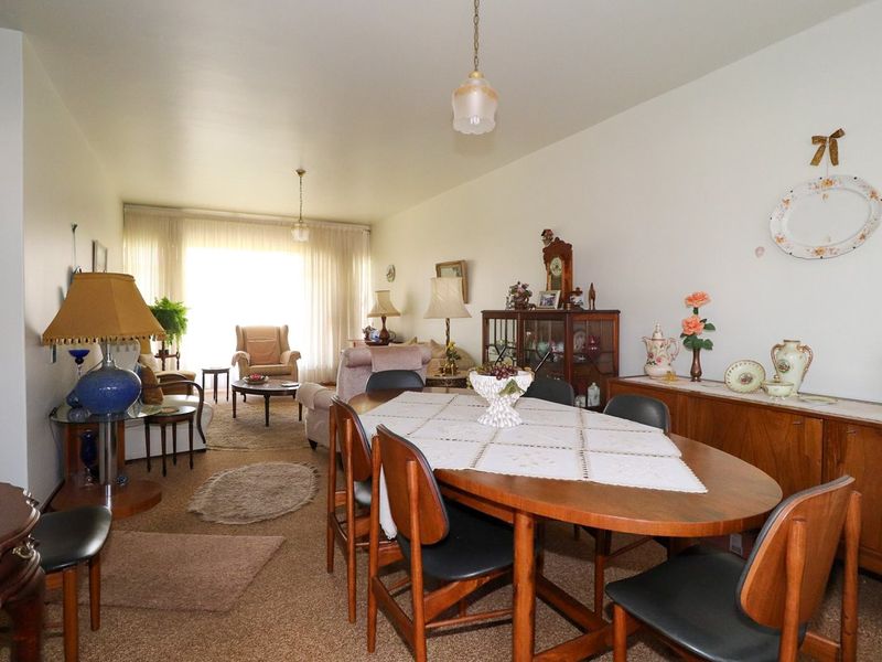 Spacious open-plan living and dining area featuring carpeted flooring and large windows that provide ample natural light.