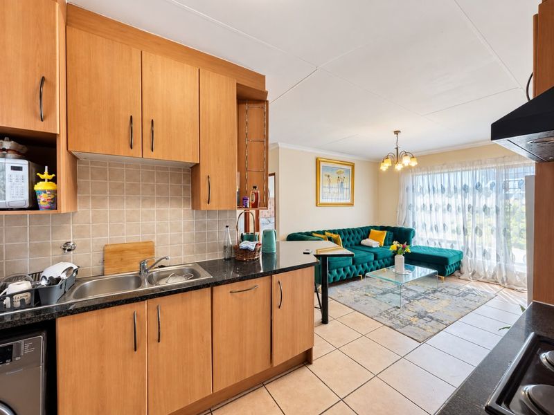 Open plan kitchen and living area featuring light wood cabinetry, granite countertops, and tiled flooring, creating a functional and connected living space.