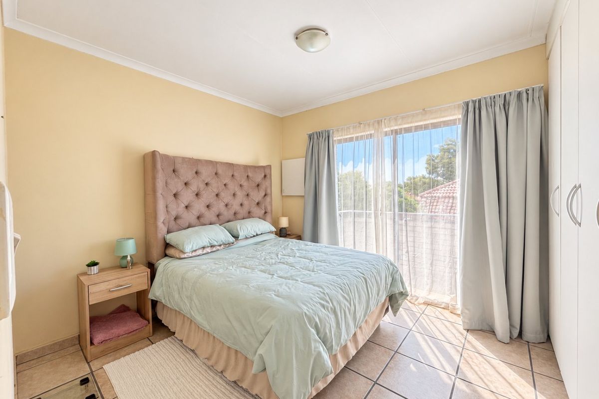 A well-lit bedroom featuring tiled flooring, built-in cupboards, and a sliding glass door providing access to an outdoor area.