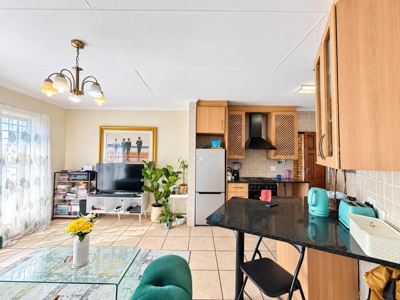 Open-plan living area featuring a functional kitchen with granite countertops, built-in cabinetry, and tiled flooring throughout, creating a cohesive and practical living space.