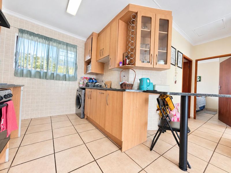 A functional kitchen featuring light wood cabinetry, granite countertops, a breakfast bar, and tiled flooring, offering a practical layout for daily use.