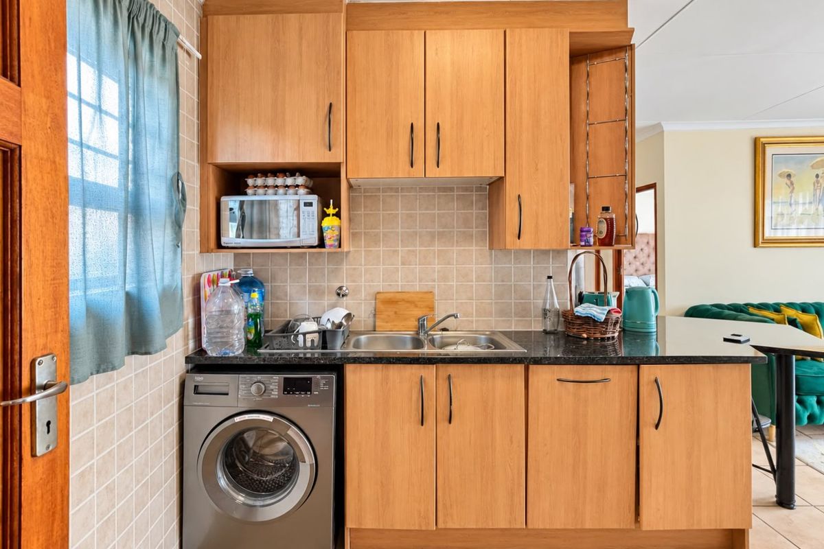 Compact kitchen featuring light wood-finish cabinetry, granite countertops, a tiled backsplash, and a dedicated space for a washing machine.