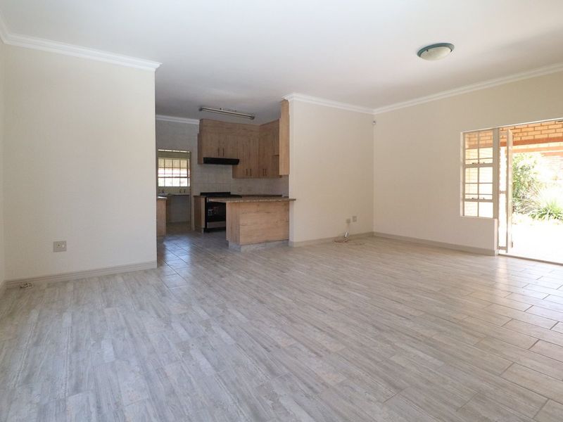 Spacious open-plan living area featuring modern tiled flooring, a functional kitchen with built-in cabinetry, and direct access to an outdoor patio area.
