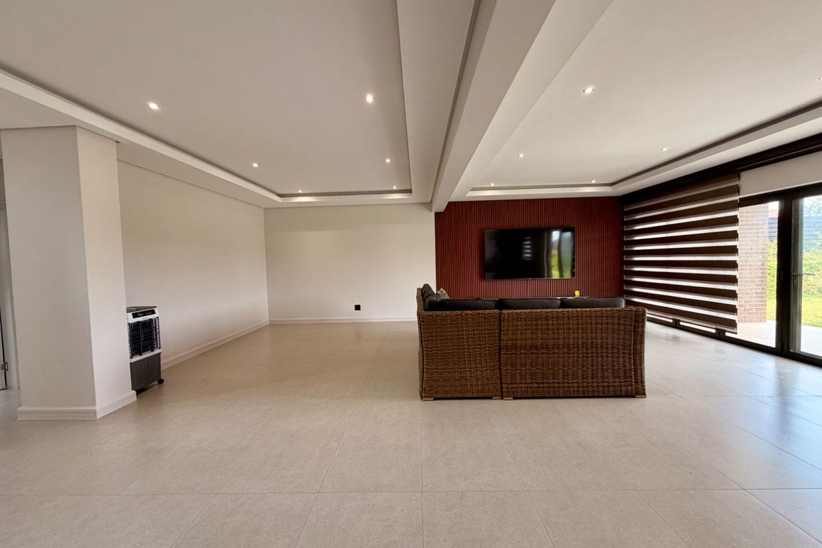 Spacious living area featuring modern tiled flooring, a striking slatted wood feature wall, recessed ceiling lighting, and large sliding doors leading to the outdoors.
