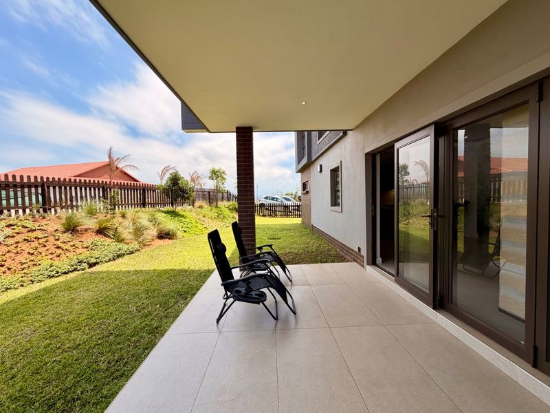 A modern covered patio featuring large format floor tiles, recessed lighting, and wide sliding glass doors providing seamless access to the garden.