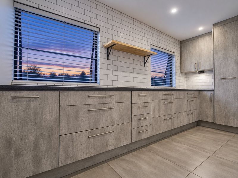 Modern kitchen featuring concrete-look cabinetry, subway tile backsplash, and large floor tiles, offering a clean, contemporary aesthetic with ample storage space.