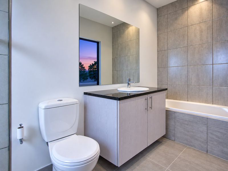 Modern bathroom featuring a vanity with granite countertop, built-in bathtub, tiled finishes, and contemporary fixtures.