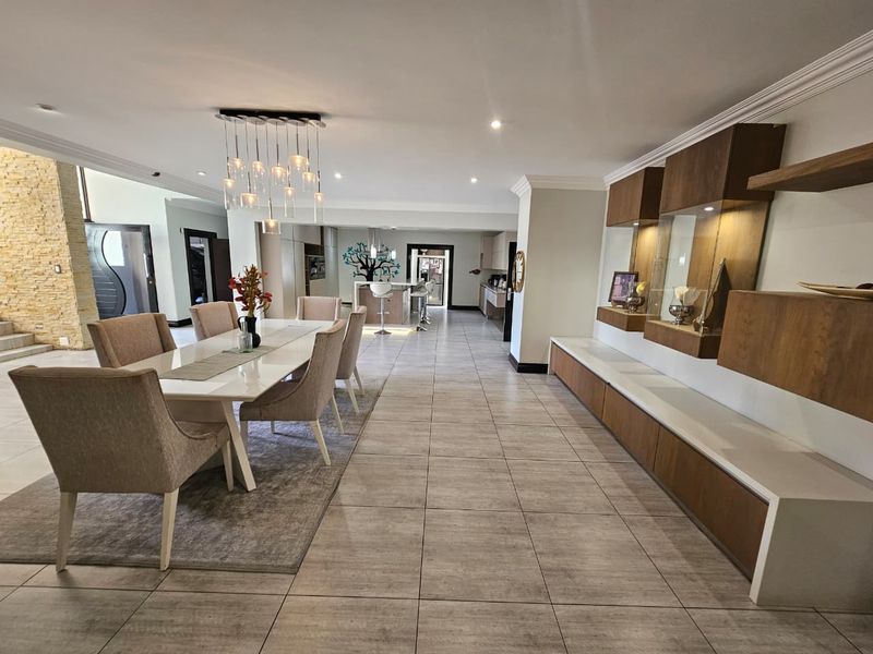 Spacious open-plan living and dining area featuring modern tiled flooring, custom built-in cabinetry, and elegant pendant lighting, creating a seamless flow throughout the home.