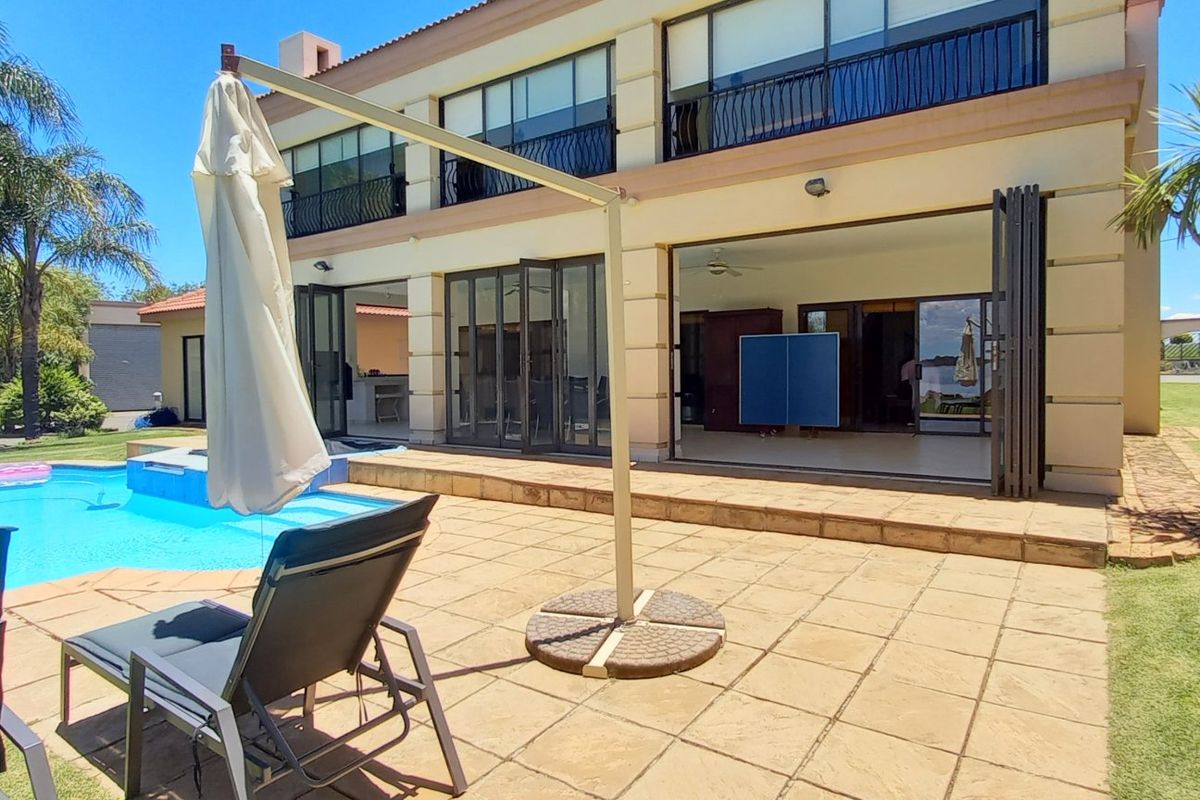 Rear view of the property featuring a tiled patio, swimming pool, and large stacking doors leading into the living area.
