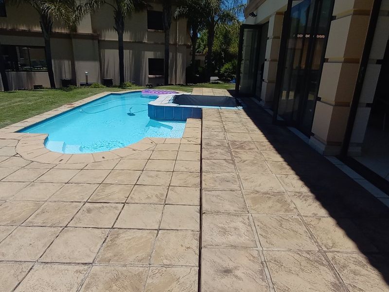 Outdoor pool area featuring a paved patio, integrated spa, and large stacking glass doors providing seamless access to the interior living space.