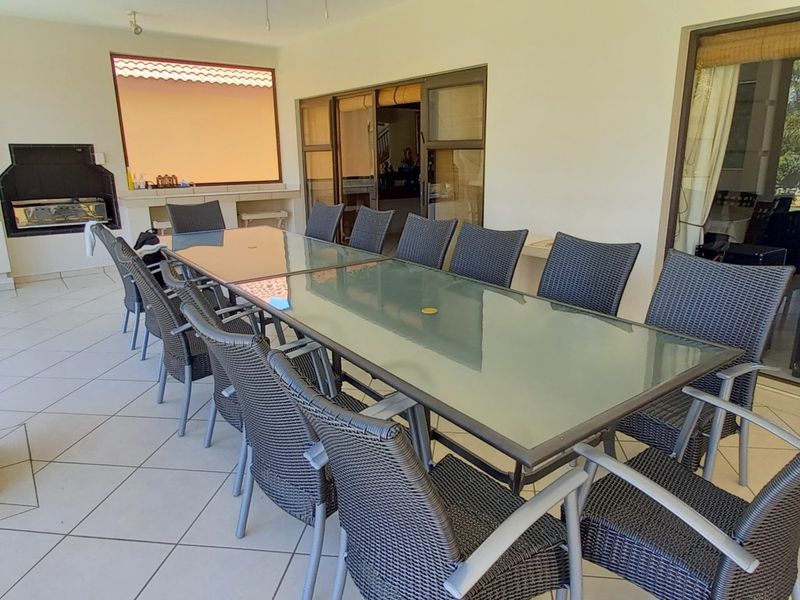 Spacious covered patio featuring tiled flooring and a built-in braai, providing an ideal space for outdoor dining and entertaining.