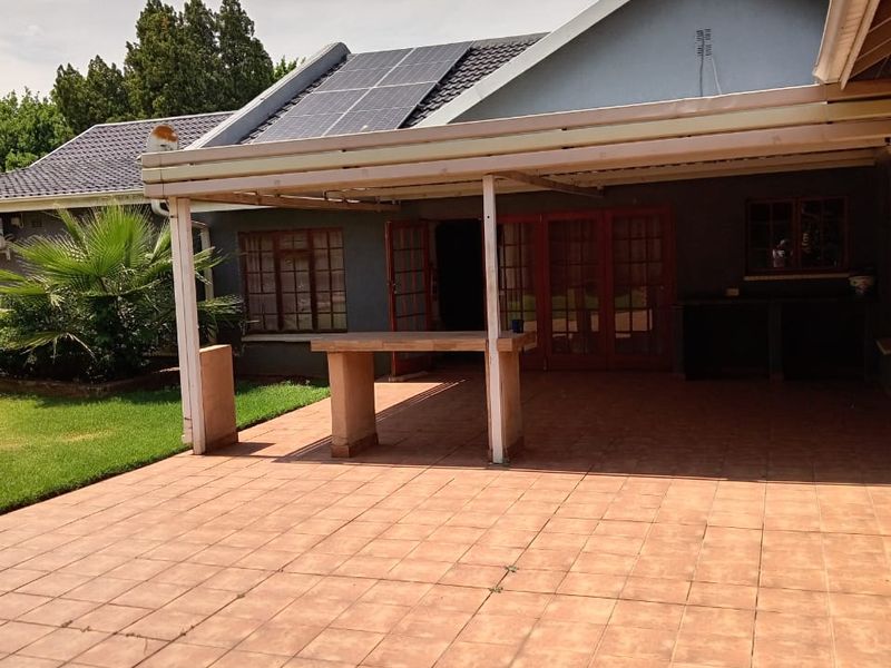 Spacious covered patio featuring tiled flooring, a built-in counter, and direct access to the home through french doors, complemented by roof-mounted solar panels.