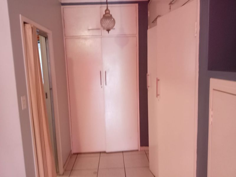 A functional hallway featuring built-in storage cupboards and tiled flooring, providing practical storage space within the home.
