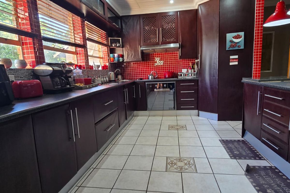 A functional kitchen featuring dark wood cabinetry, red tiled backsplash, and ample counter space, providing a practical layout for daily cooking and meal preparation.