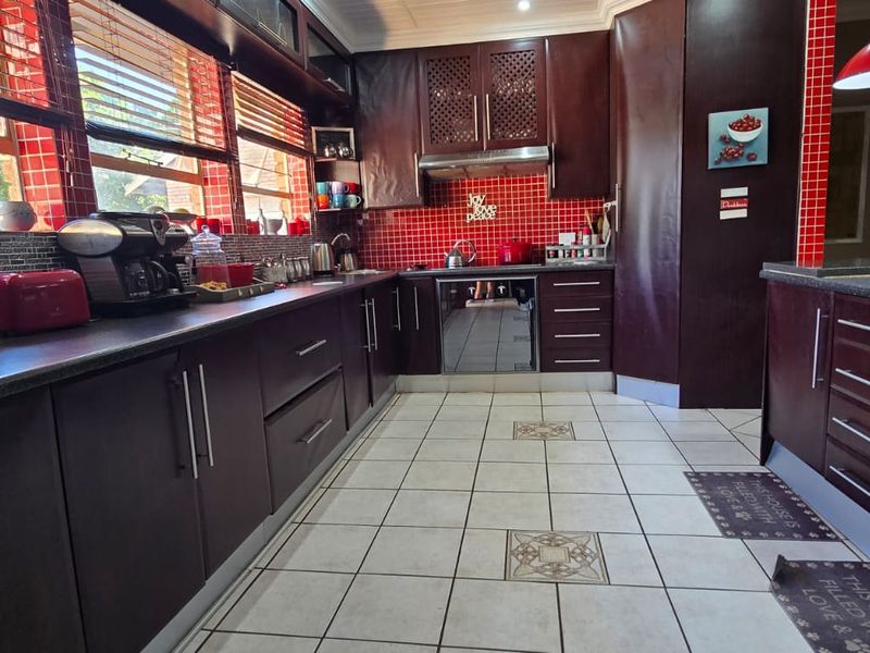 A functional kitchen featuring dark wood cabinetry, red tiled backsplash, and ample counter space, providing a practical layout for daily cooking and meal preparation.