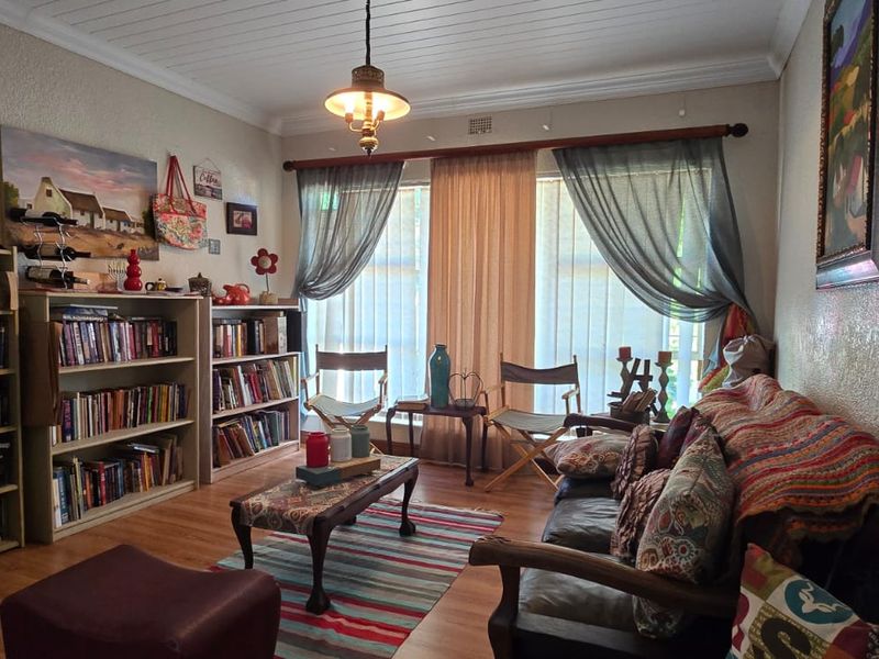 A cozy living room featuring timber laminate flooring, a classic tongue and groove ceiling with cove cornice, and a central pendant light fixture.