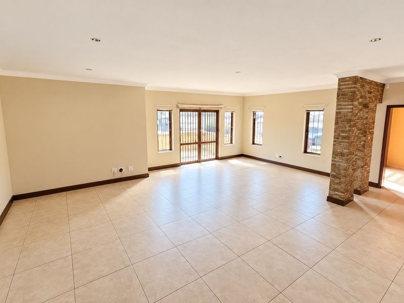 Spacious, light-filled living area featuring neutral tiled flooring, a decorative stone-clad pillar, and direct access to the exterior through a secure sliding door.