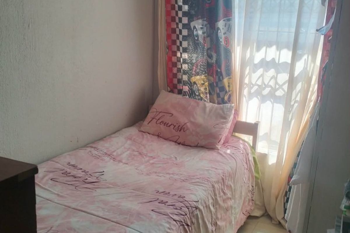 A compact bedroom featuring tiled flooring and a window fitted with a security gate, providing natural light.