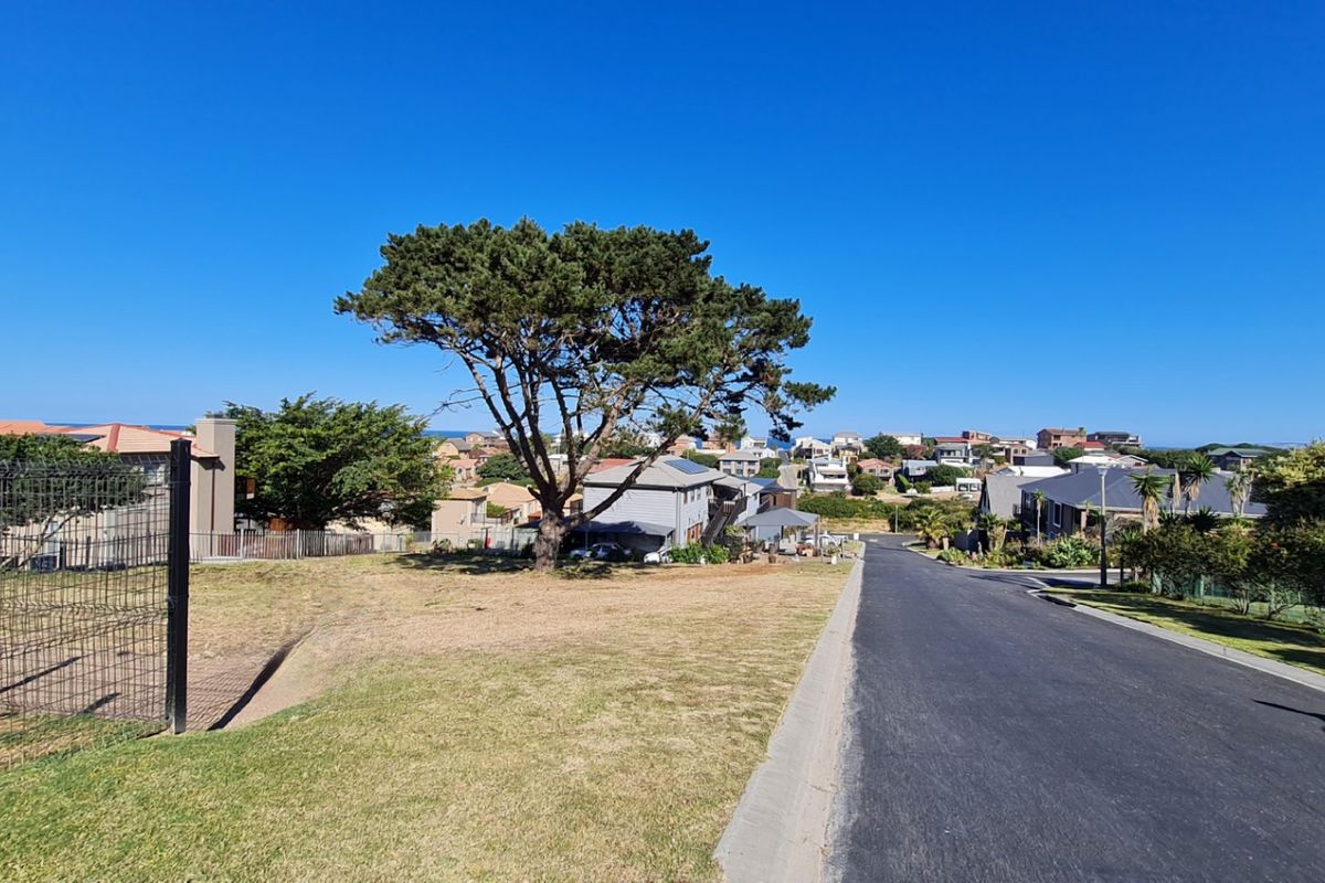 A street-level view of a residential area featuring an asphalt road, concrete curbing, and surrounding neighborhood properties.