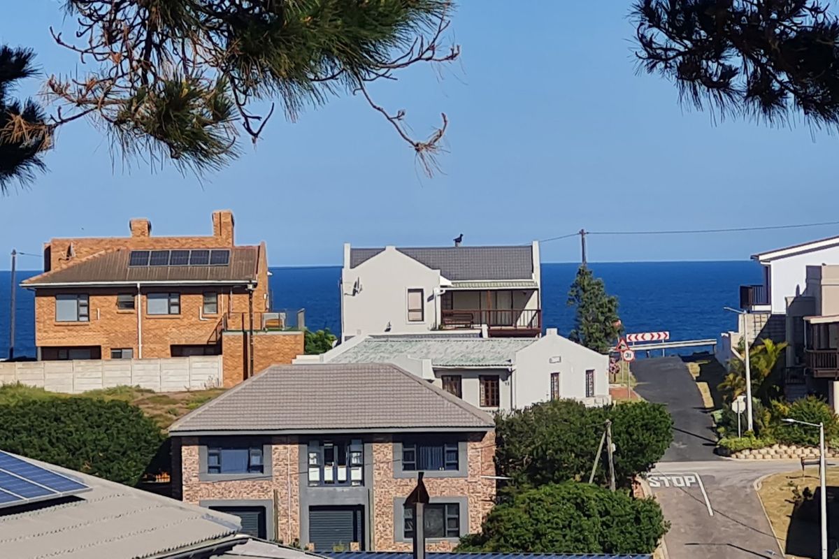 A scenic elevated view overlooking a coastal residential neighborhood with a clear horizon line of the ocean.
