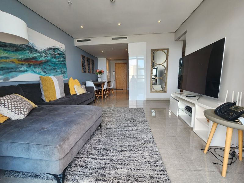 A modern open-plan living and dining area featuring tiled flooring, recessed downlighting, and integrated ducted air conditioning.