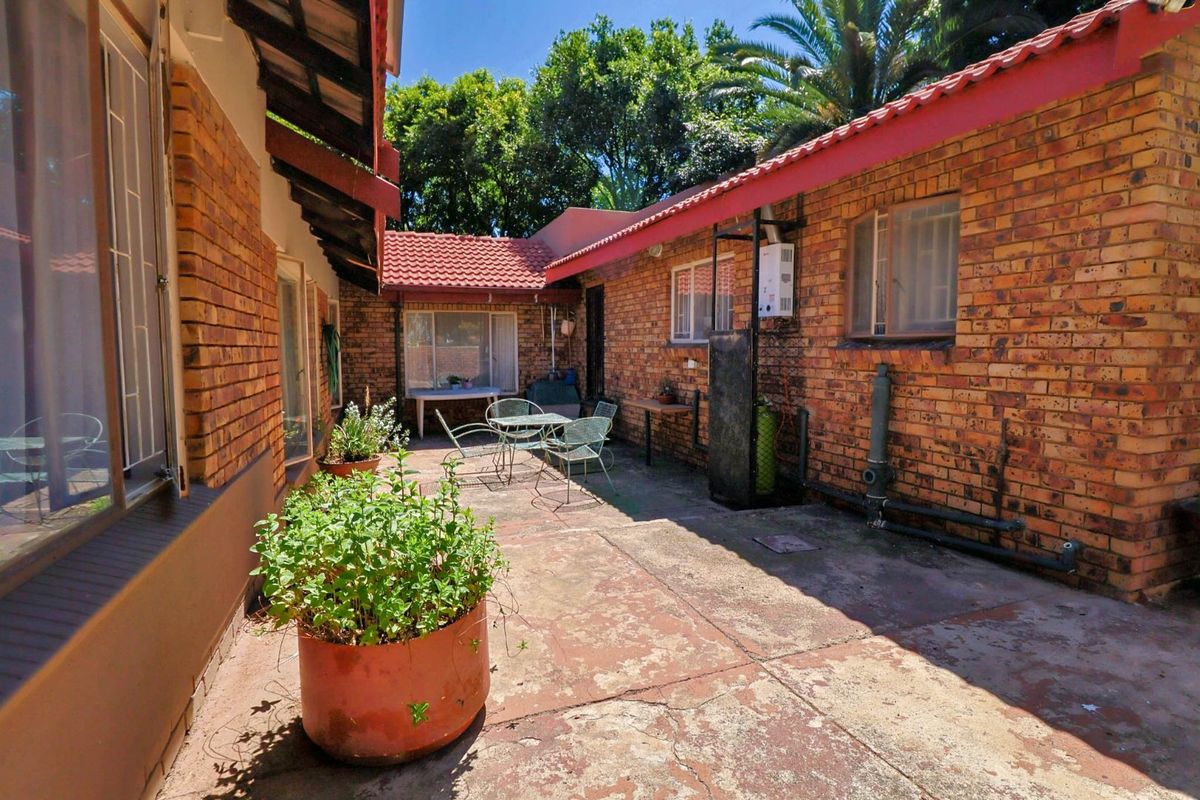 A private rear courtyard featuring exposed brick walls, tiled roofing, and paved flooring, offering a functional outdoor space for relaxation.