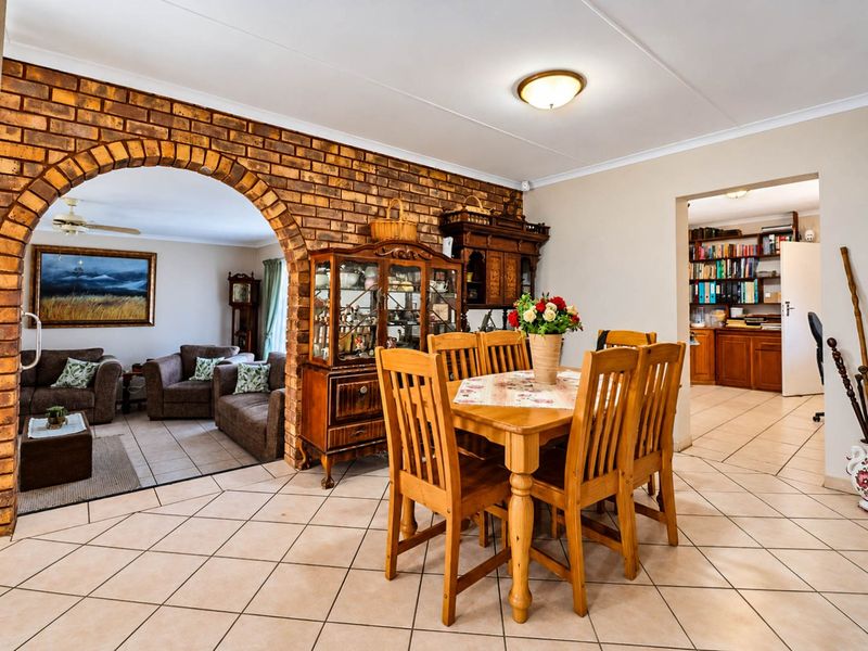 Dining area featuring ceramic floor tiles and a distinctive exposed brick archway leading into the adjacent living space.