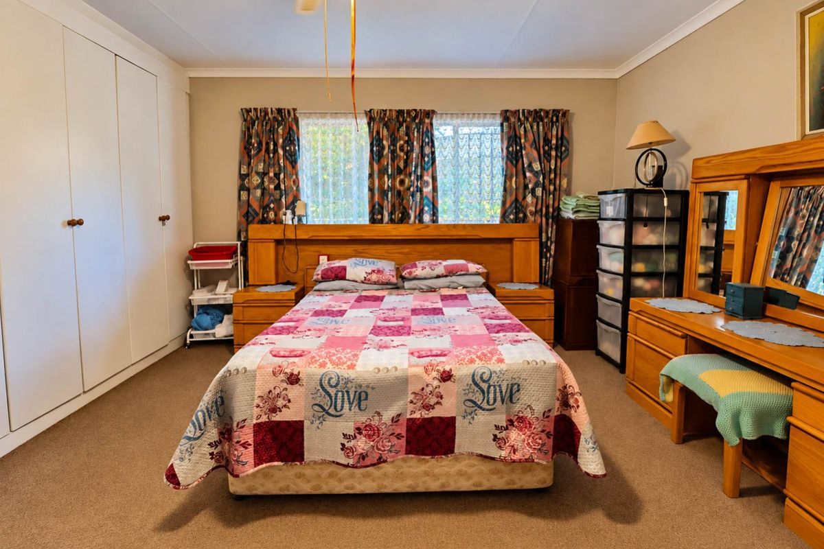 Spacious bedroom featuring neutral walls, carpeted flooring, built-in cupboards, and a ceiling fan, offering a functional and comfortable living space.
