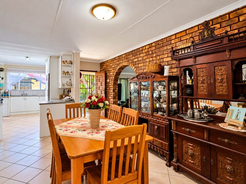 Open plan dining area featuring an exposed brick feature wall, arched entryway, and ceramic floor tiles, seamlessly connecting to the adjacent kitchen space.