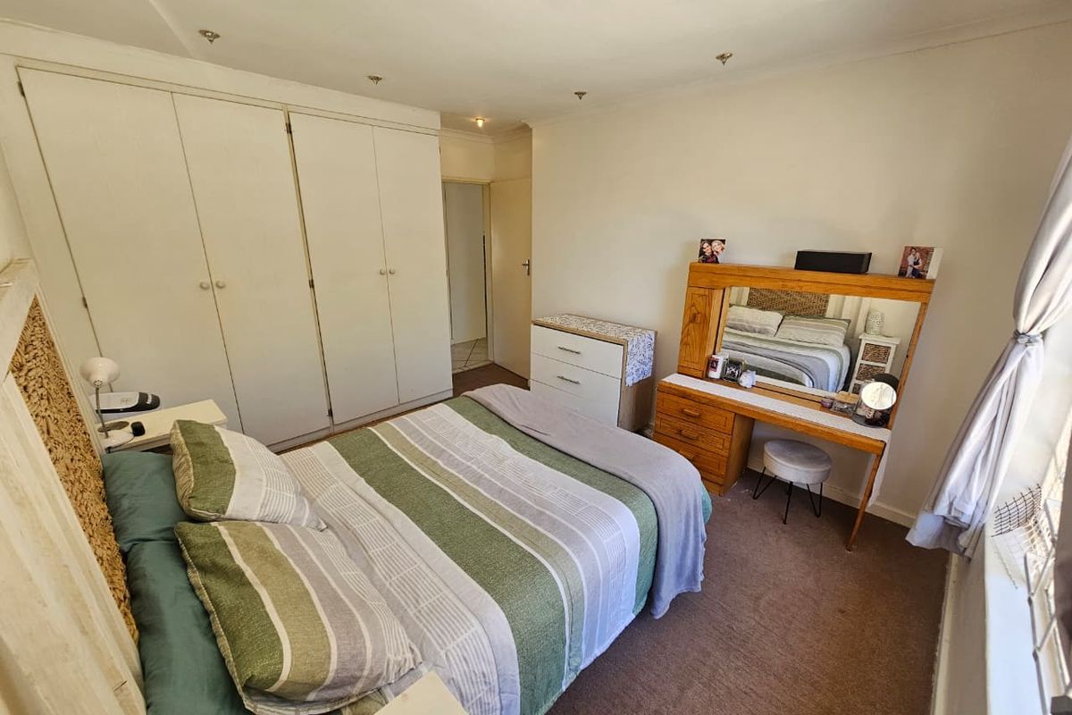 A functional bedroom featuring built-in cupboards and recessed downlighting, offering a neutral base for potential interior updates.