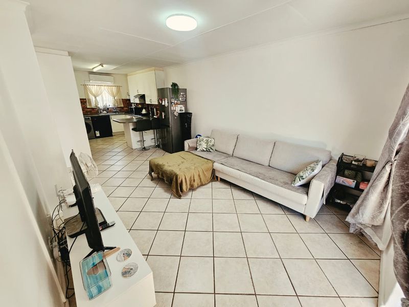 Open plan living area featuring tiled flooring and a functional kitchen with built-in cabinetry and an island counter.