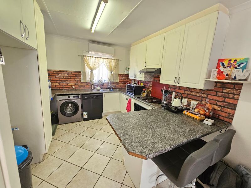 Functional kitchen featuring granite countertops, brick-style backsplash, built-in cabinetry, and integrated appliances, including a breakfast nook area.