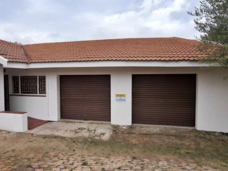 Exterior view of a double garage with roller doors, featuring a tiled roof and security bars on the adjacent windows.