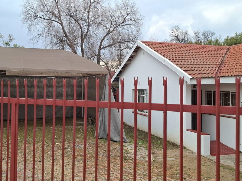 Front view of a residential property featuring a tiled roof, garage, and secure metal perimeter fencing.