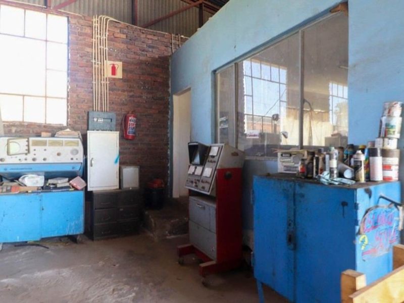 Industrial utility space featuring exposed brick walls, steel-framed windows, and an internal glass partition, suitable for workshop or storage use.
