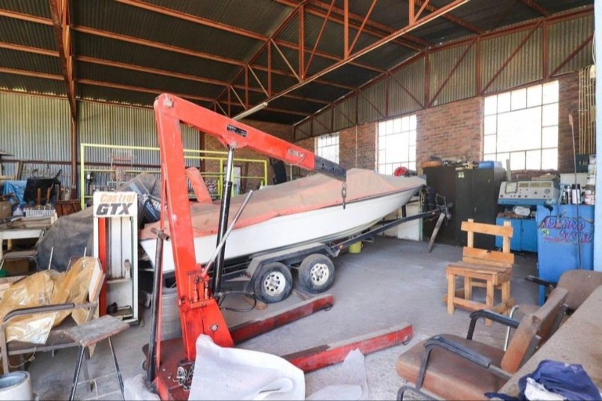 Spacious industrial garage featuring exposed steel roof trusses, brick walls, and concrete flooring, suitable for workshop or storage use.