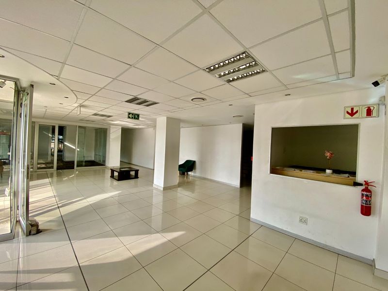 Spacious industrial entry area featuring tiled flooring, a suspended ceiling with recessed lighting, and a built-in reception counter.