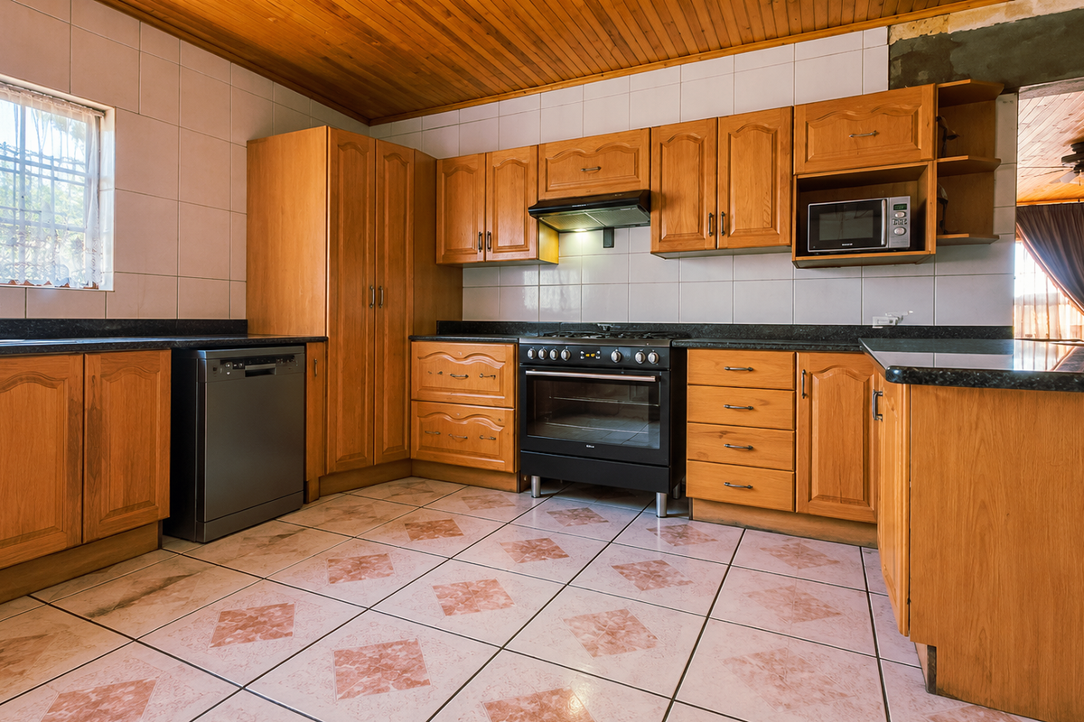 A functional kitchen featuring wooden cabinetry, granite countertops, built-in appliances, and tiled finishes, with an unfinished wall section above the upper cabinets.