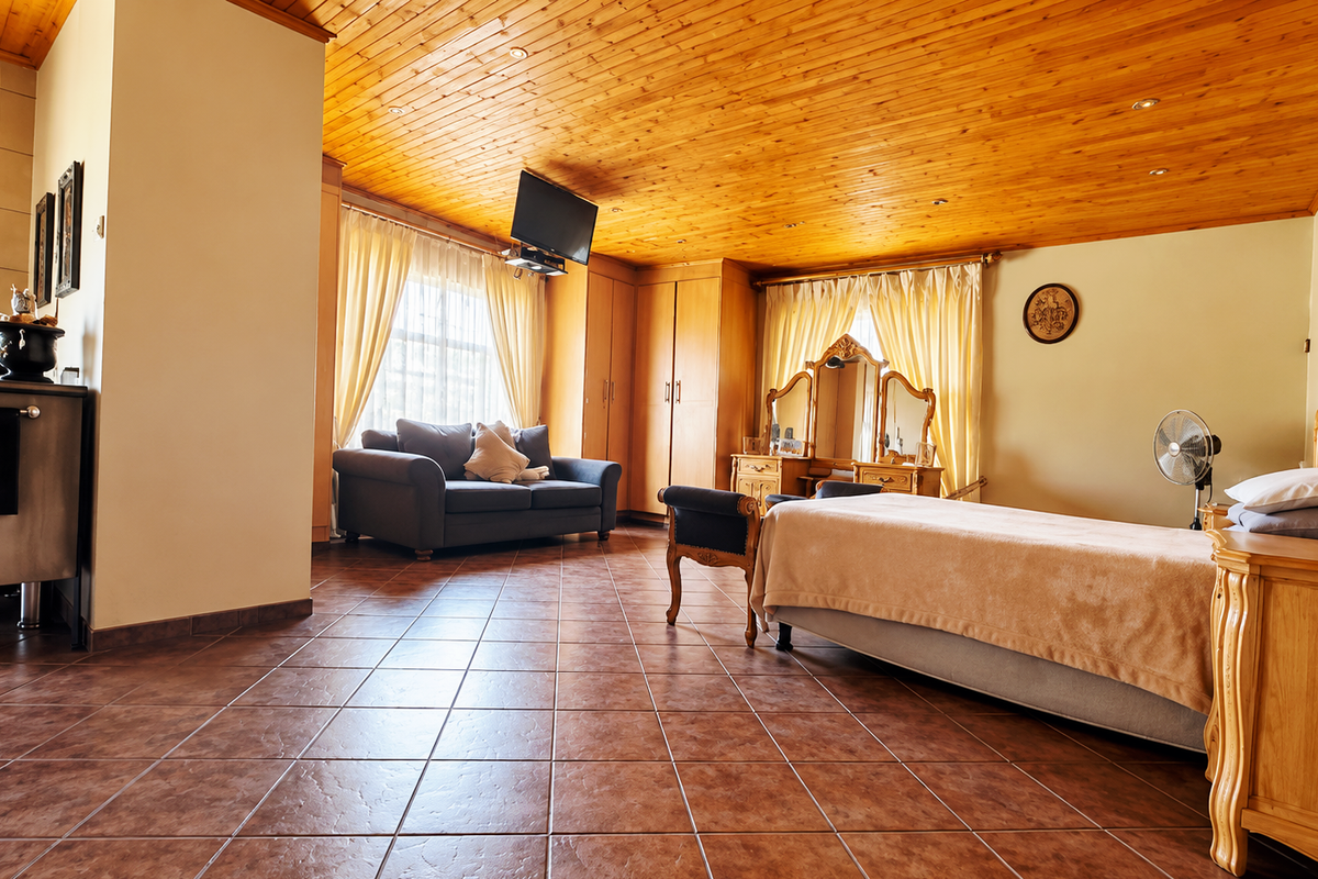Spacious bedroom featuring a warm timber-clad ceiling, tiled flooring, and integrated built-in cabinetry, offering a comfortable and functional living space.