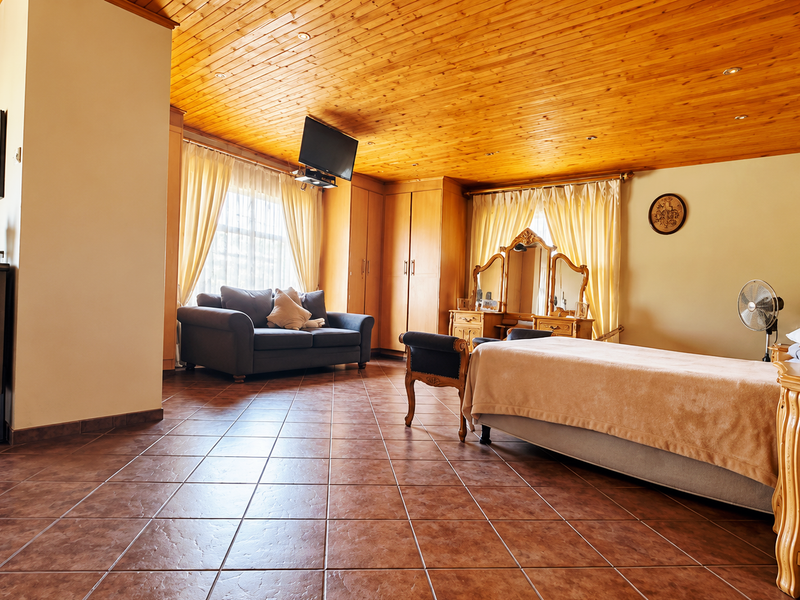 Spacious bedroom featuring a warm timber-clad ceiling, tiled flooring, and integrated built-in cabinetry, offering a comfortable and functional living space.