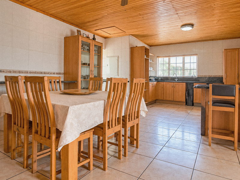 Spacious open-plan kitchen and dining area featuring wooden ceiling, tiled floors, ample cabinetry, and a functional breakfast bar island.
